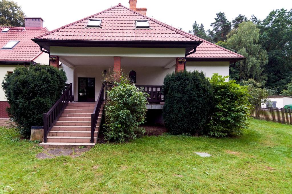 a house with a porch and stairs in the yard at Leśniczówka Agroturystyka Gabriela Pieczka in Tuchola