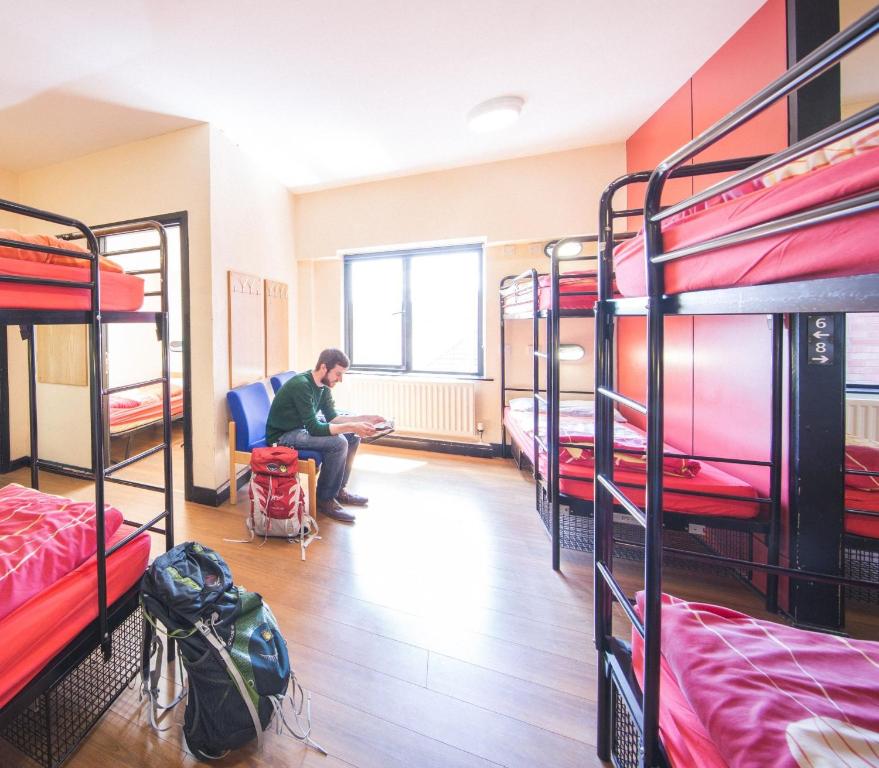 a man sitting in a room with bunk beds at Belfast International Youth Hostel in Belfast