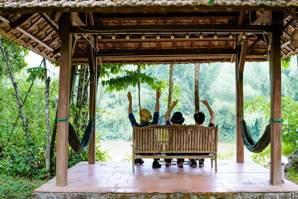 un grupo de tres personas sentadas en un columpio en Green Hope Lodge en Cat Tien