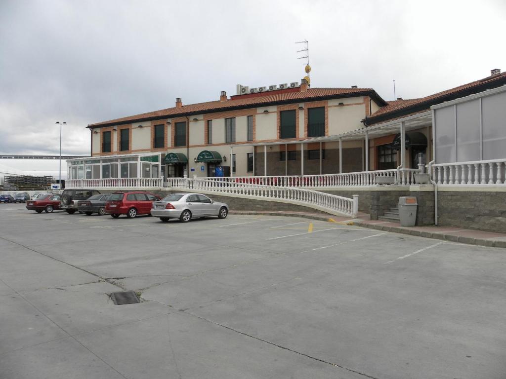 a building with cars parked in a parking lot at Hostal Las Fuentes in Arévalo