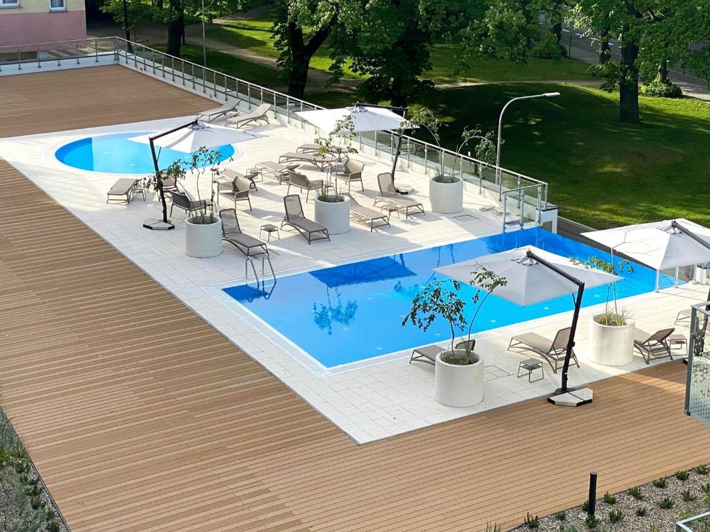 科沃布熱格的住宿－Apartamenty NAVIGATOR- NADMORSKIE TARASY PORT，游泳池旁设有椅子和遮阳伞