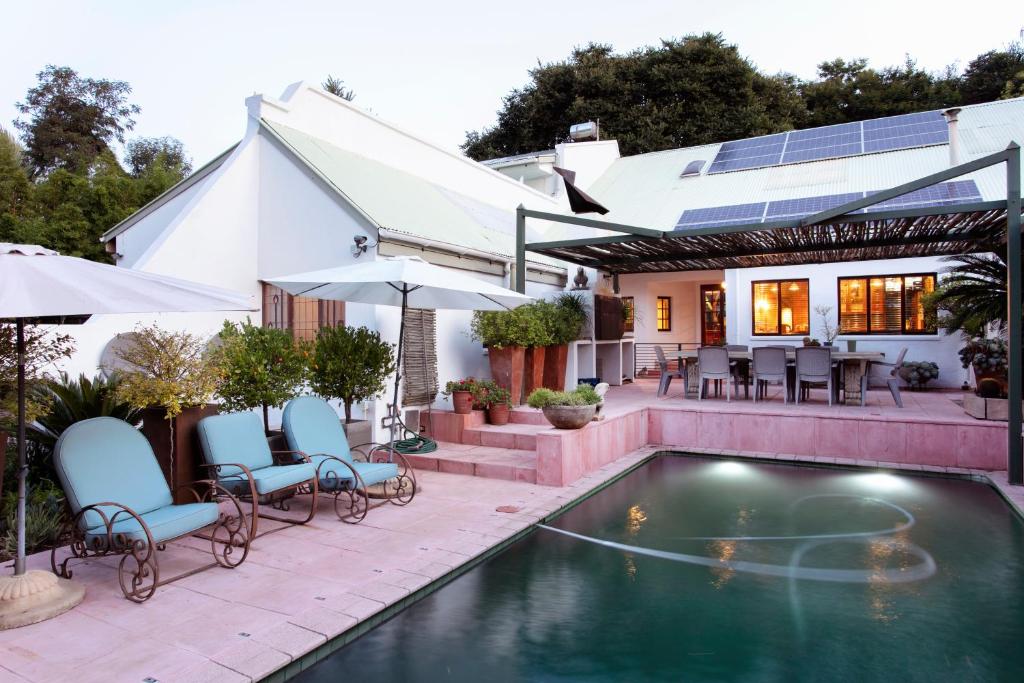 a house with a swimming pool with chairs and umbrellas at Waterkloof Apartments in Pretoria