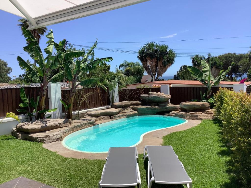 einen Pool in einem Garten mit zwei Liegestühlen in der Unterkunft Hoyo 19 in Marbella