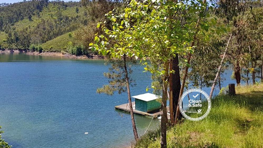 a small house sitting on the side of a lake at Casa RioTempo + Jangada in Tomar