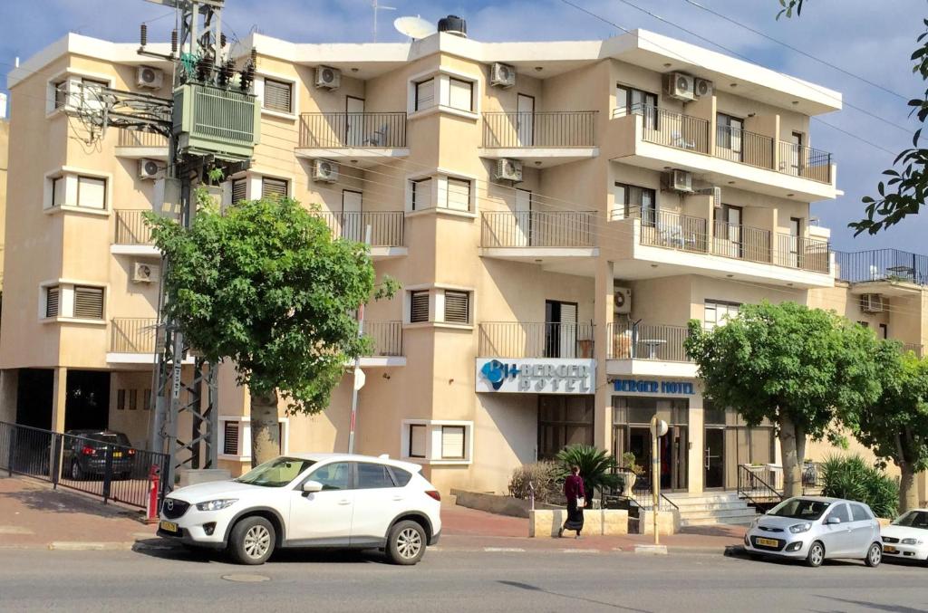 un grande edificio con macchine parcheggiate di fronte di Berger Hotel a Tiberias