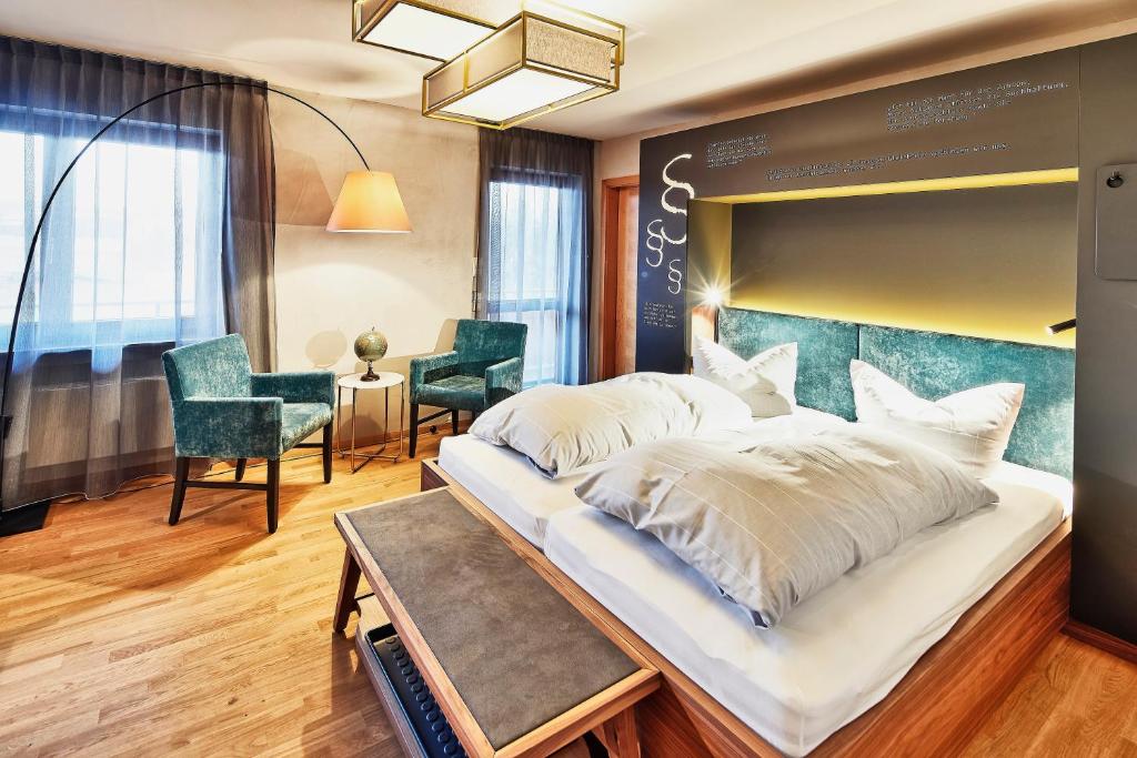 une chambre d'hôtel avec un grand lit et des chaises dans l'établissement Biohotel-Restaurant Rose, à Hayingen
