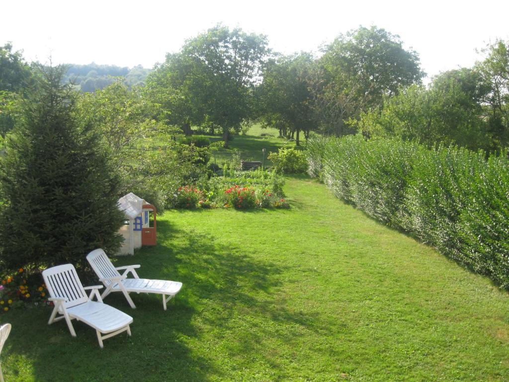 two white chairs sitting in the grass in a garden at Murmure des buis in Corveissiat