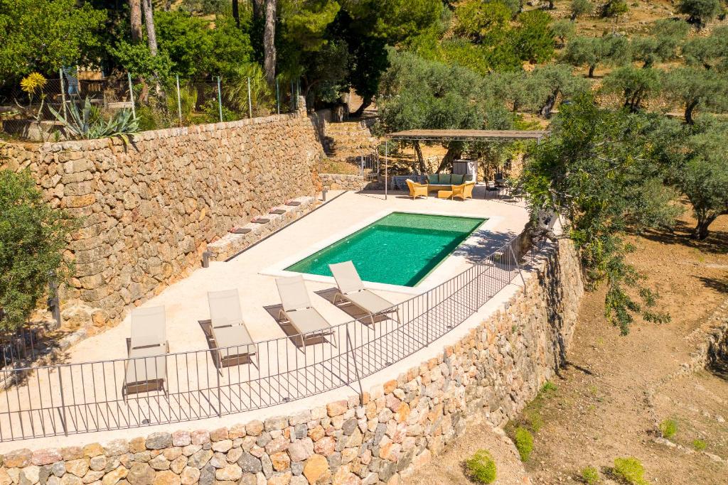 una piscina al aire libre con sillas y una pared de piedra. en Raco de Soller, en Sóller