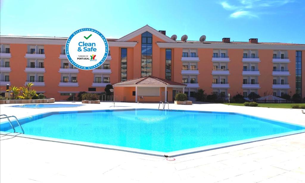 a hotel with a large swimming pool in front of a building at Riviera Hotel in Carcavelos