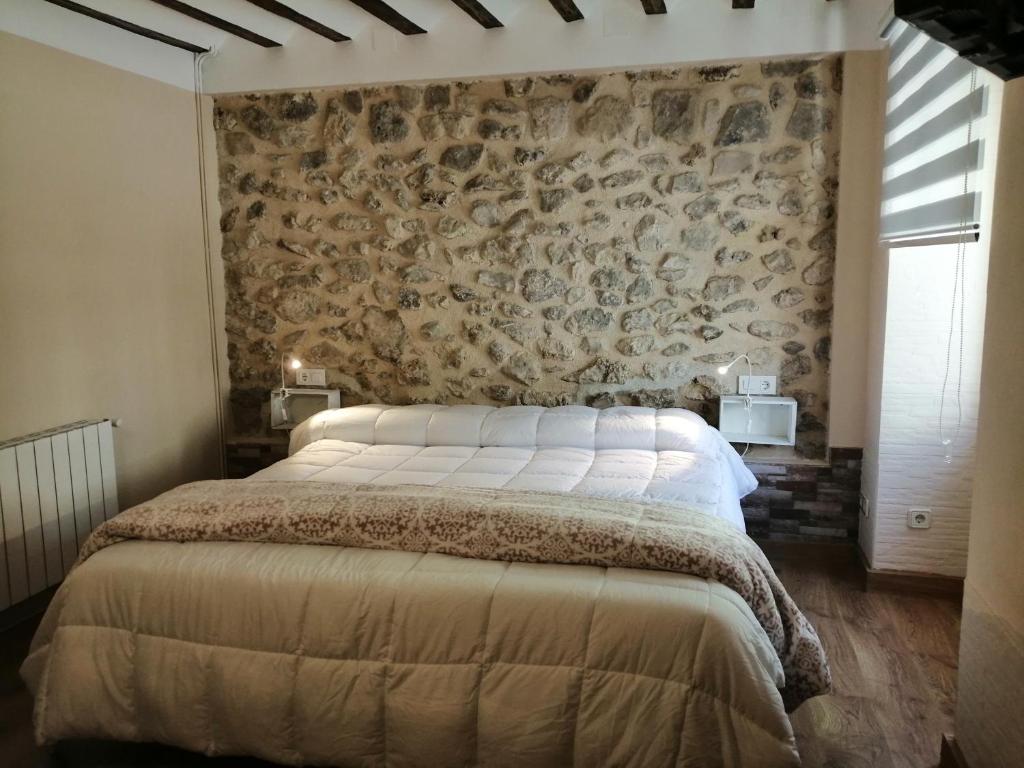 1 dormitorio con cama y pared de piedra en Habitacion tienda de felipe EL DESPACHO, en Pontones