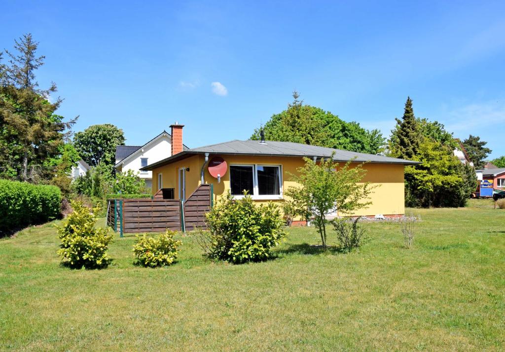 une petite maison jaune dans un champ d'herbe dans l'établissement Ferienhaus Sabine mit Kamin und So, à Baabe