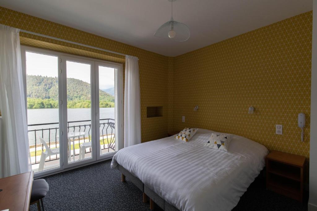 a bedroom with a bed and a large window at Hotel Bellevue in Chambon-sur-Lac