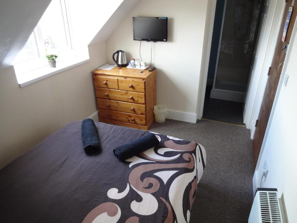 a bedroom with a bed and a dresser and a television at Travellers Rest Motel in Ingoldmells
