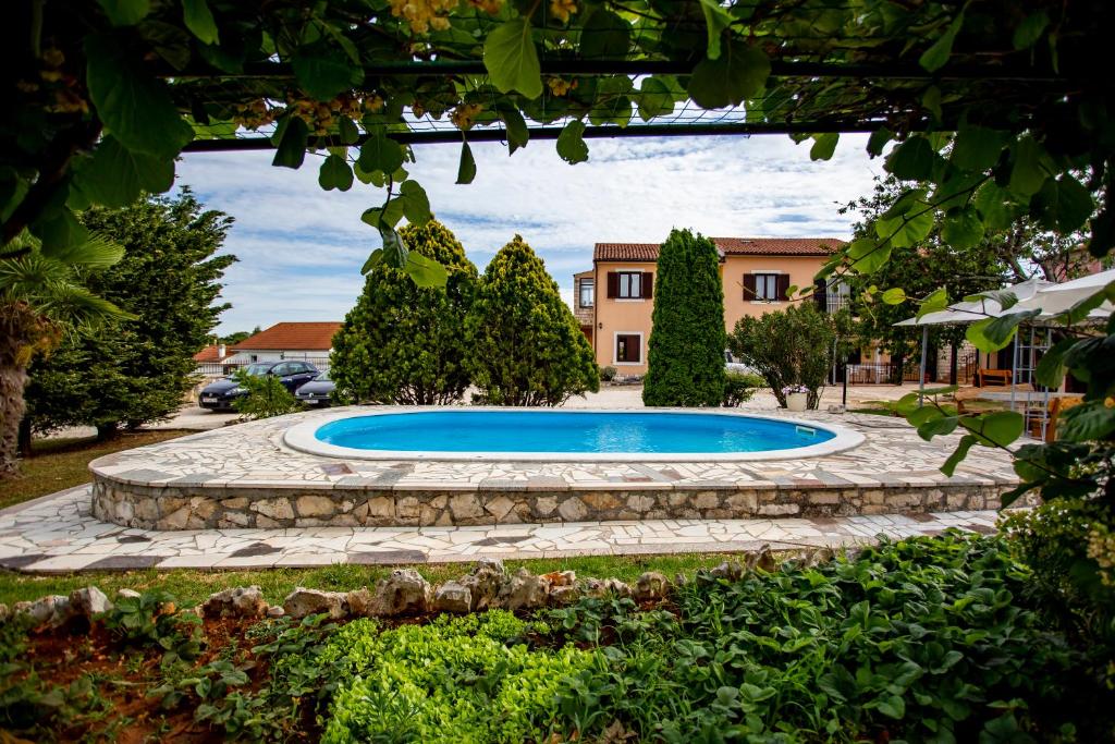 a swimming pool in a yard with a stone walkway at Apartmani Jurman in Matohanci