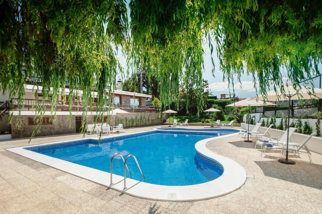 una piscina con sillas y un árbol encima en Finca la Cabaña, en Gójar