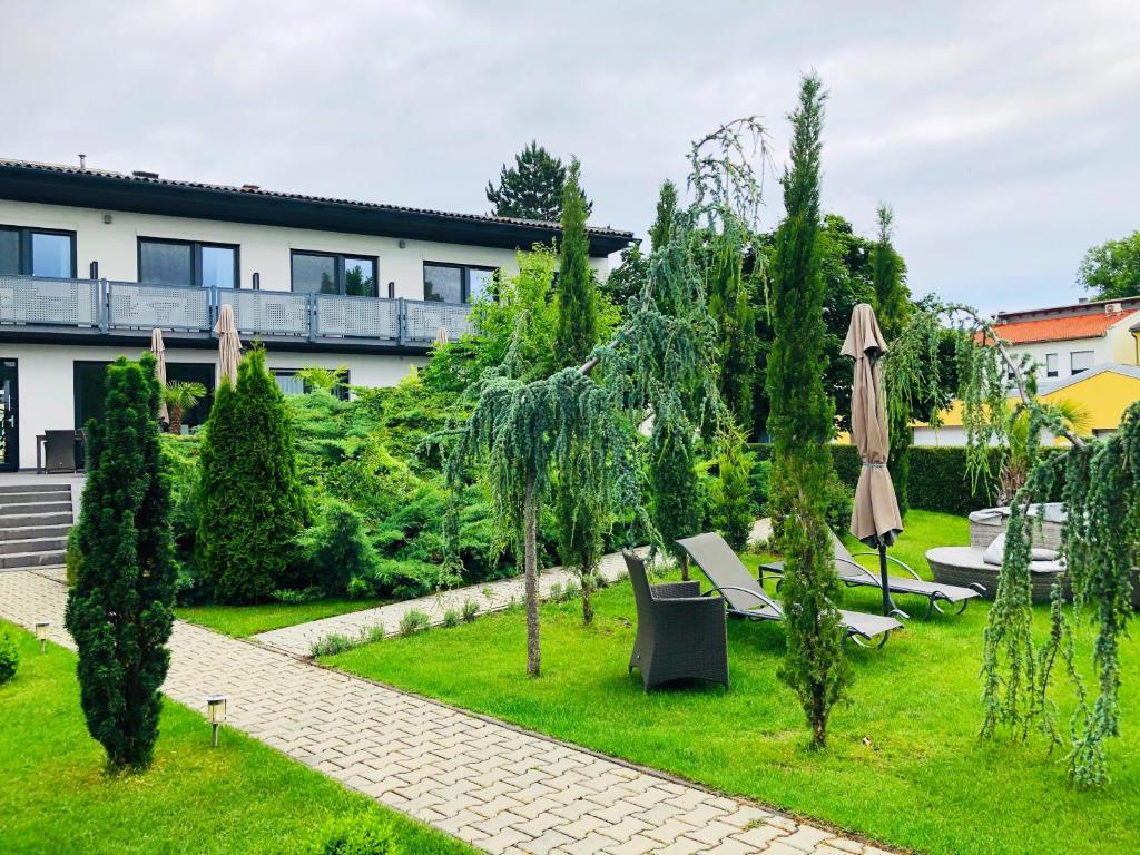 a garden with an umbrella and chairs and trees at Haus Pannonsee in Podersdorf am See