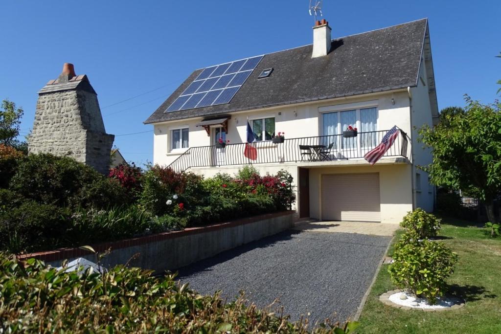 een wit huis met zonnepanelen op het dak bij La Maison Blanche in Saint-Laurent-sur-Mer