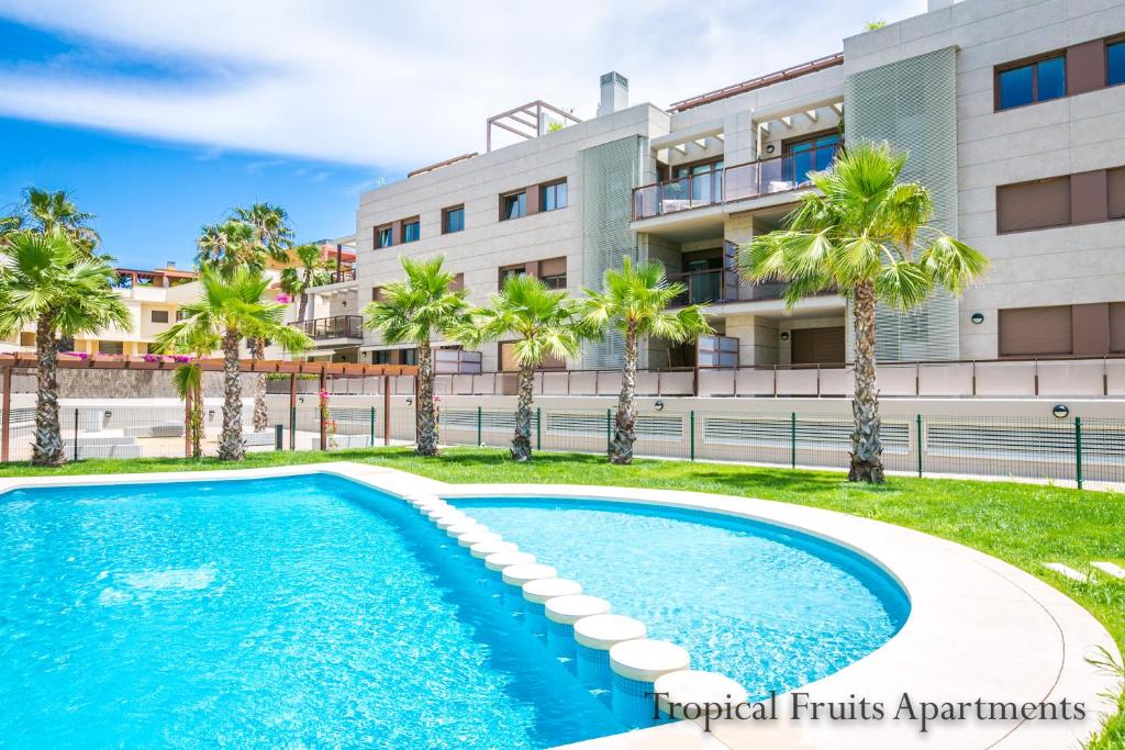 einem Pool vor einem Gebäude mit Palmen in der Unterkunft Apartment Lime Golden Star, Javea in Jávea