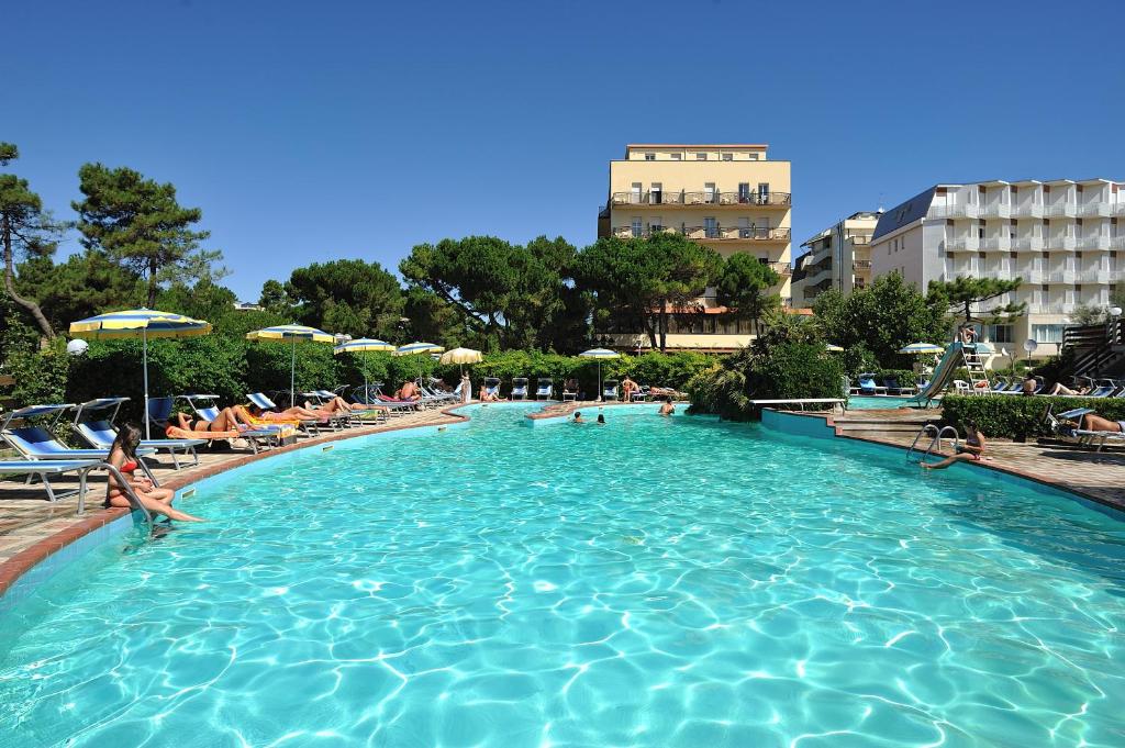 una gran piscina con gente sentada en ella en Hotel Ausonia, en Milano Marittima