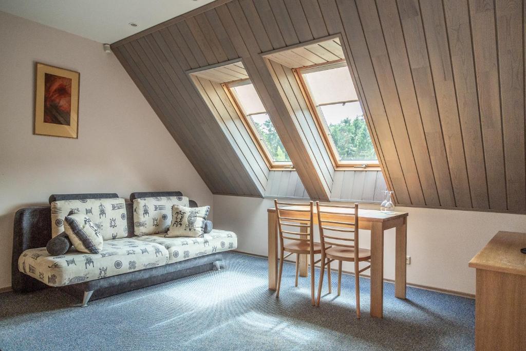 a attic room with a couch and a table and chairs at Nerija in Nida