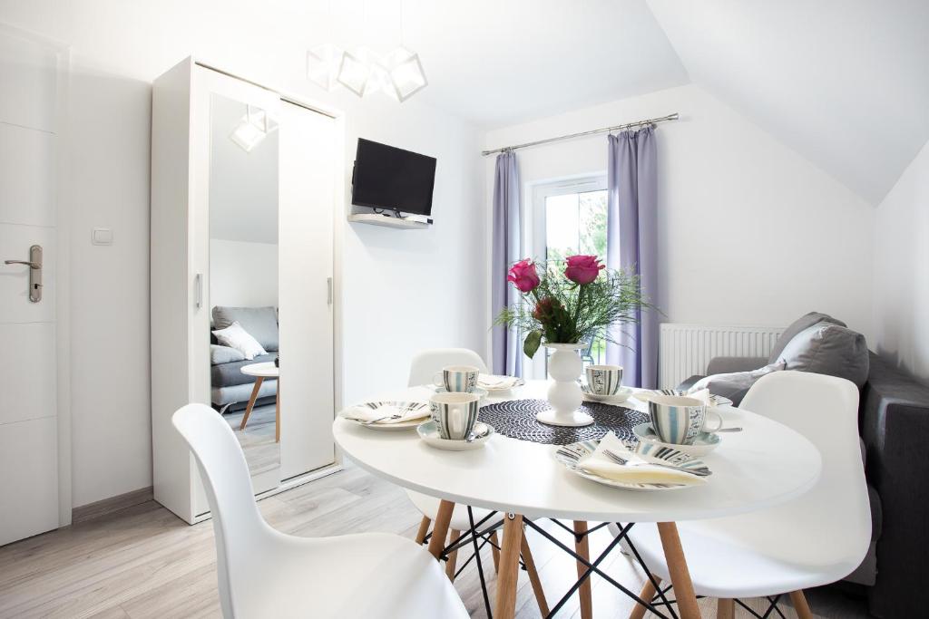 uma sala de jantar branca com uma mesa e cadeiras brancas em Apartamenty Pod Cisem em Kudowa-Zdrój
