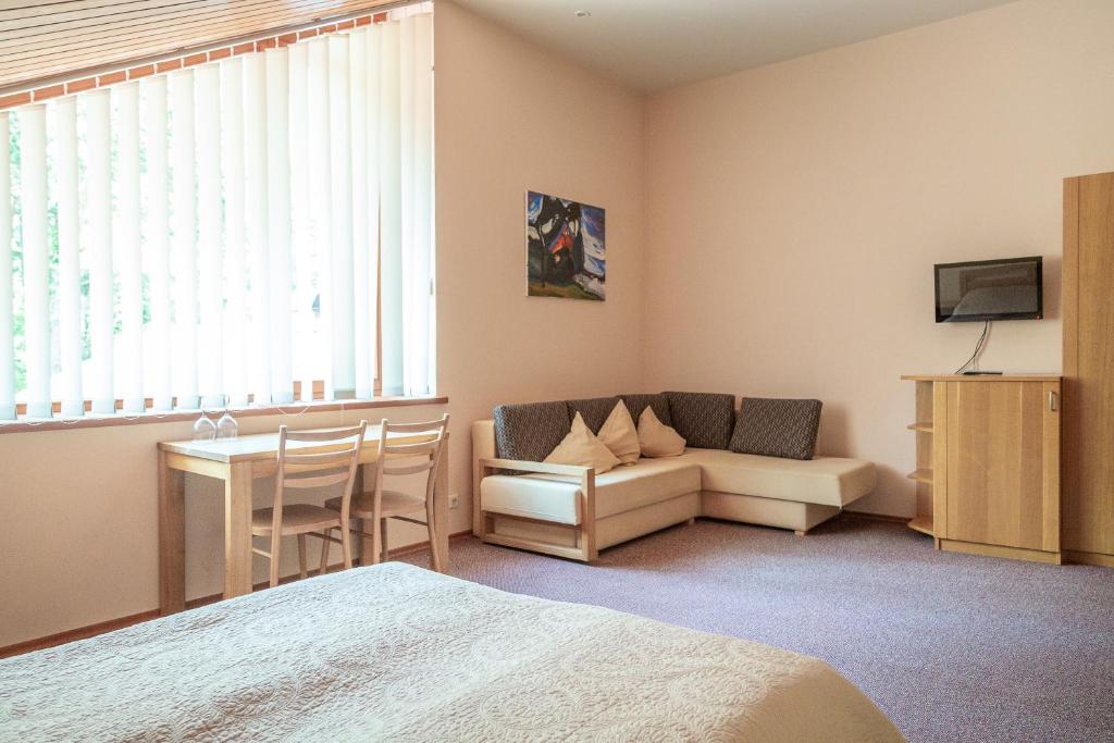 a bedroom with a couch and a table and a tv at Nerija in Nida