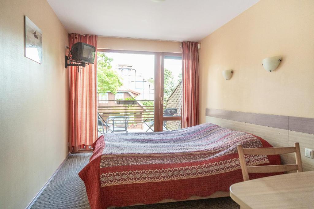 a bedroom with a bed and a window and a table at Nerija in Nida