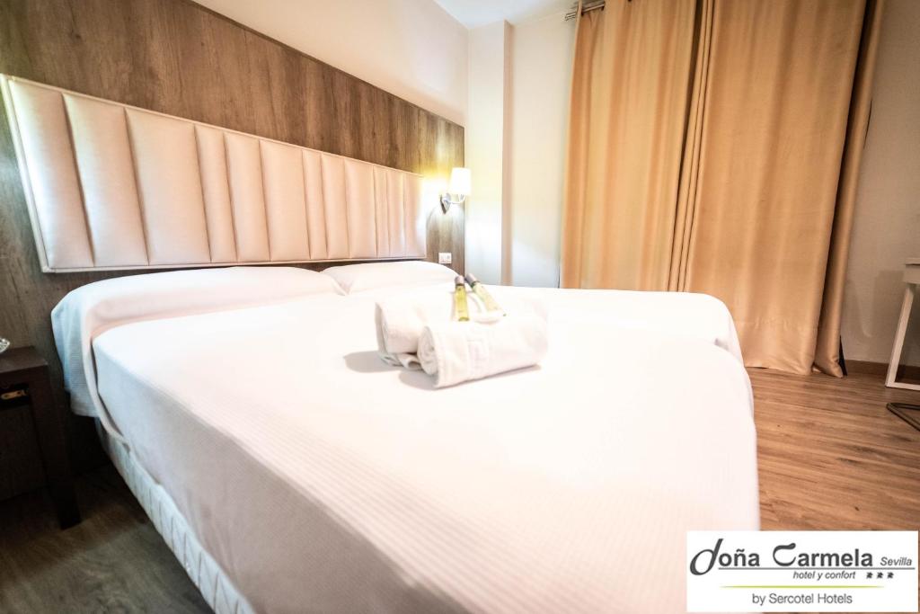 a large white bed with two towels on it at Hotel Sercotel Doña Carmela in Seville