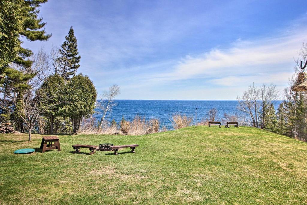 three picnic tables on a grassy hill overlooking the ocean at Lake Superior Beachfront Home - 15 Mi to Duluth! in Clifton