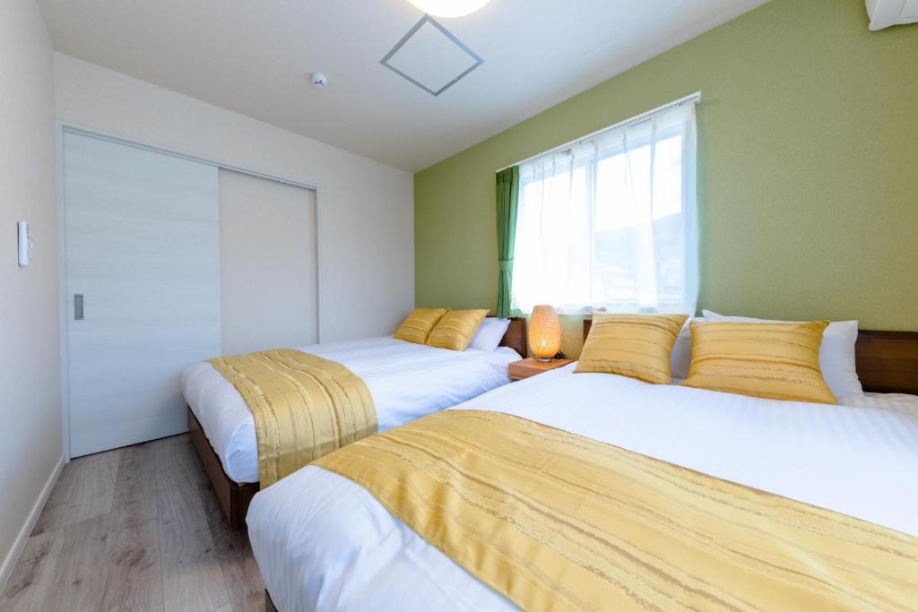 two beds in a room with green walls at Minamitsuru-gun - House - Vacation STAY 82677 in Fujikawaguchiko