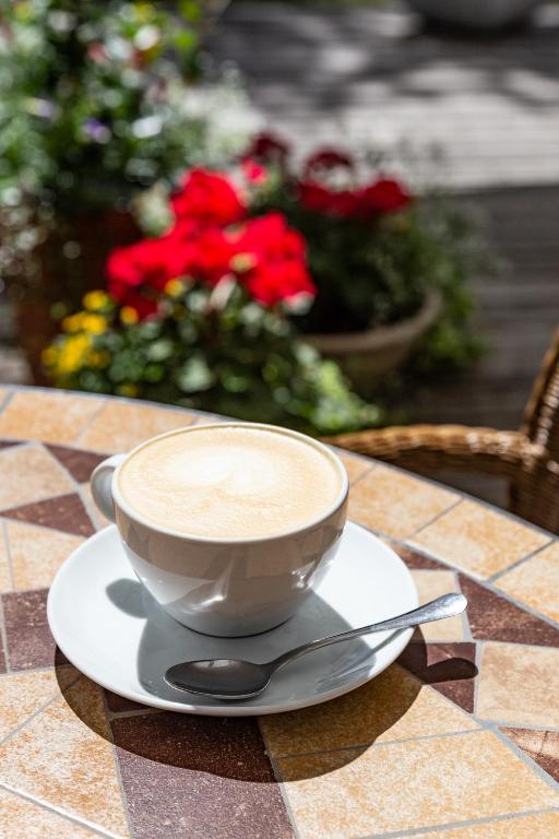 a cup of coffee on a plate on a table with flowers at Nerija in Nida
