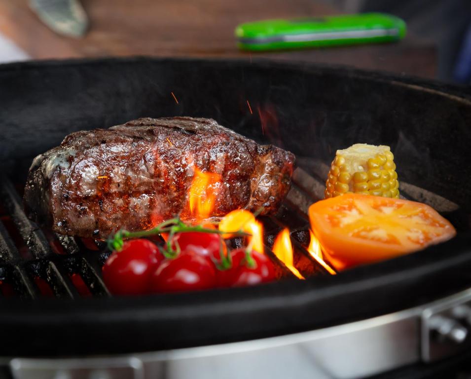 a steak and tomatoes and corn on a grill at Nerija in Nida