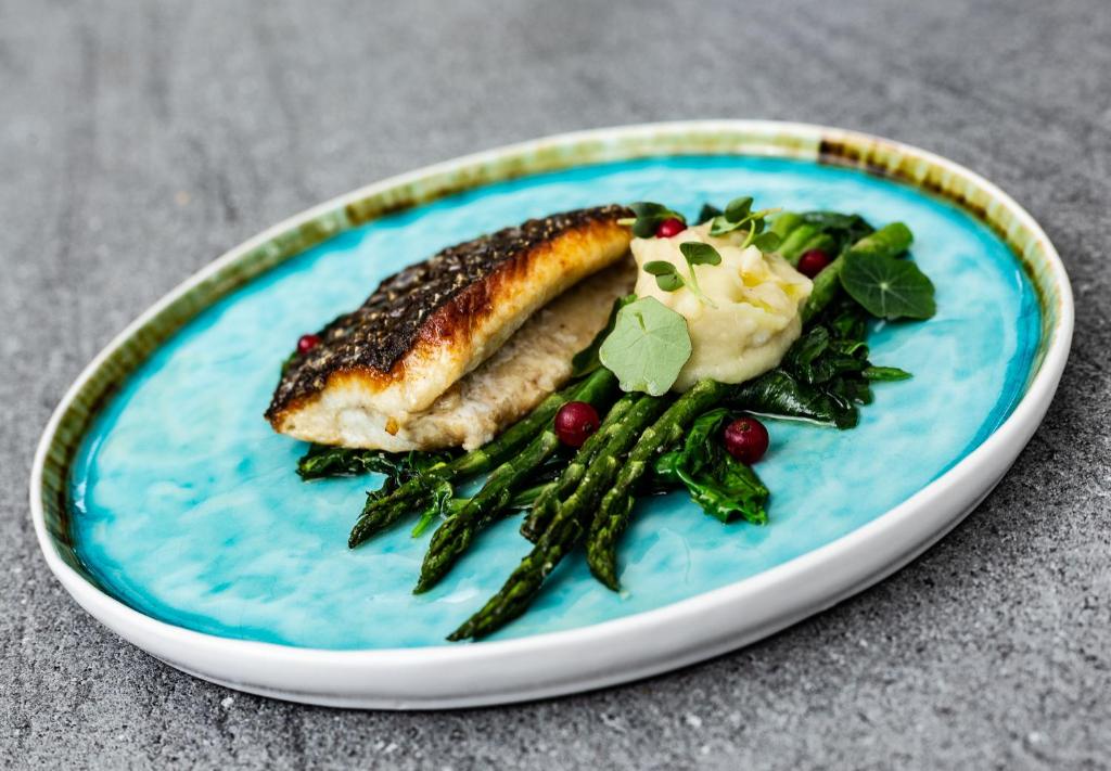 a plate of food with a piece of fish and greens at Nerija in Nida