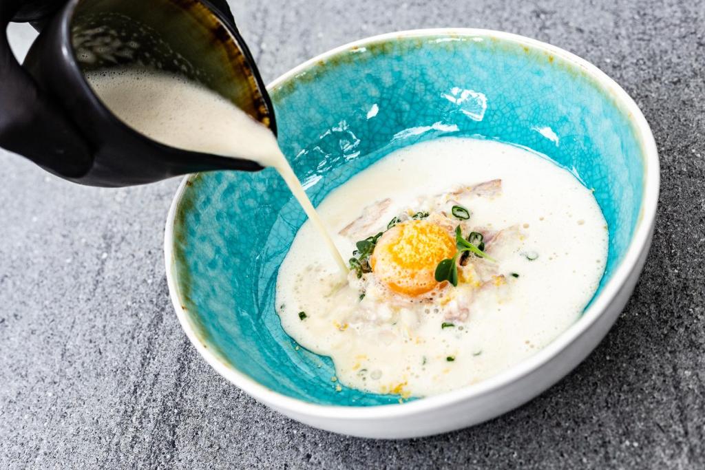 an egg is being poured into a bowl of soup at Nerija in Nida