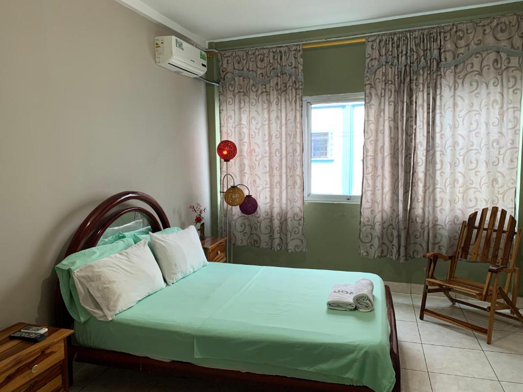 Un dormitorio con una cama verde con una silla y una ventana en Residencial Turístico Rio Guayas, en Guayaquil