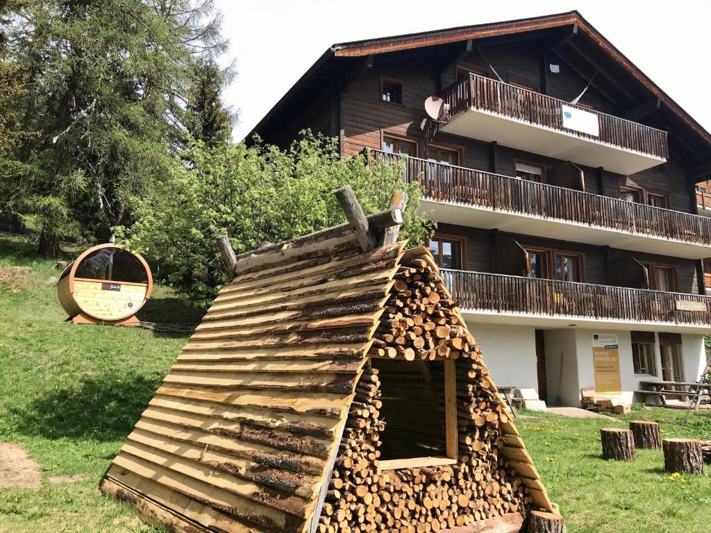 un cumulo di legna da ardere di fronte a un edificio di Lärchenwald Lodge a Bellwald
