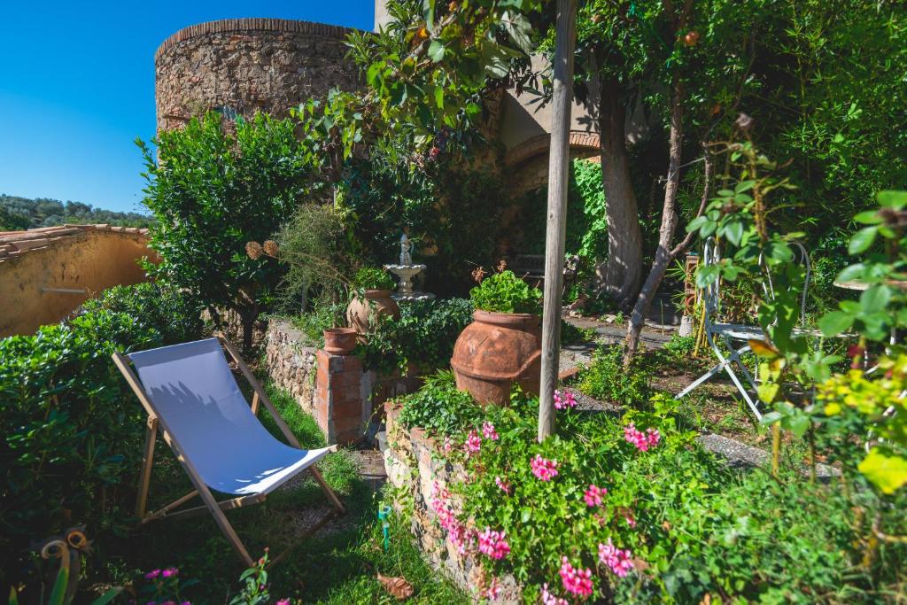 una silla en un jardín con flores y plantas en La Casa nel Borgo, en Bibbona