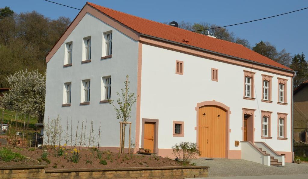 un edificio blanco con techo rojo en Ferienwohnungen Zur Tenne, en Beckingen
