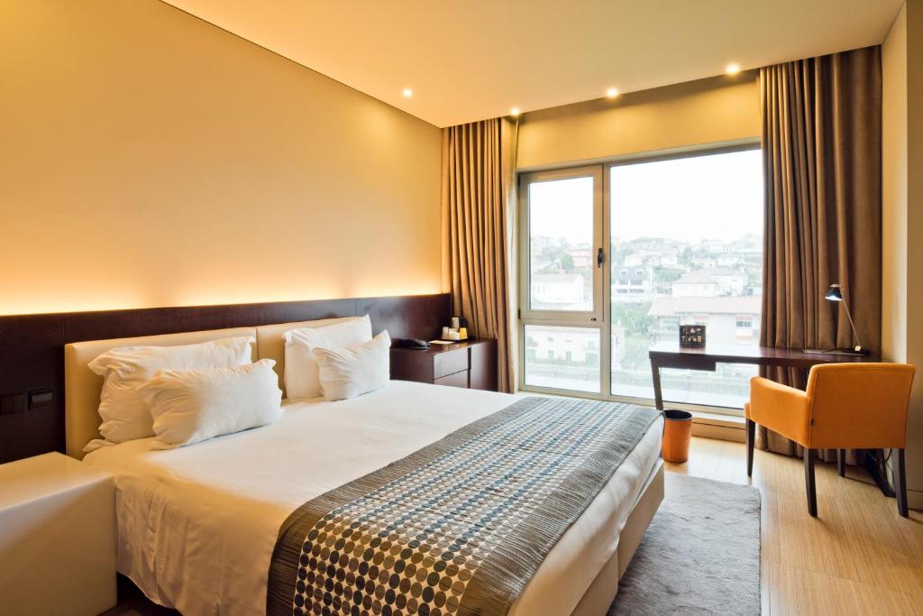 a hotel room with two beds and a large window at Golden Tulip São João da Madeira Hotel in São João da Madeira