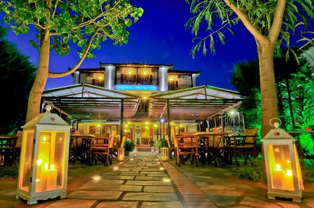 a resort with lights and tables and chairs at night at Pegasus Hotel & Coastal Cafe in Kala Nera