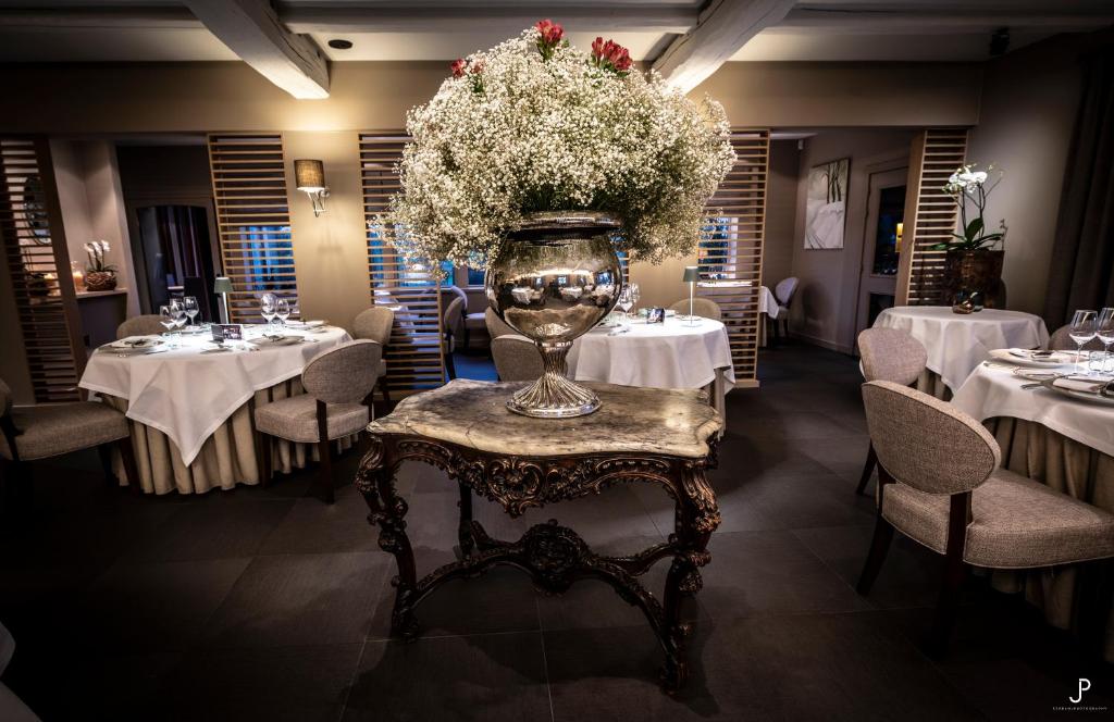 un comedor con mesas y un jarrón de flores en Hostellerie Gilain, en Achêne