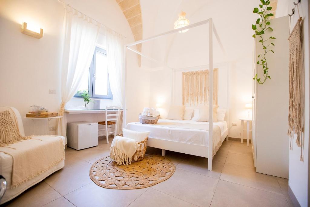 a white bedroom with a bed and a chair at La Casa Della Zia in San Pancrazio Salentino