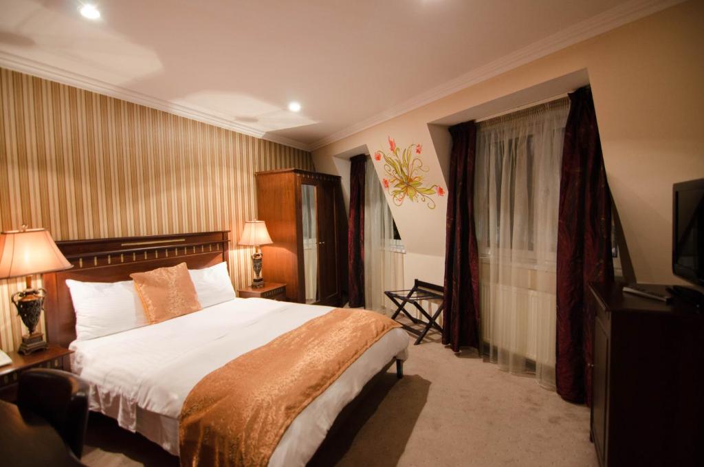 een hotelkamer met een bed en een televisie bij Hotel Boutique Monaco in Boekarest