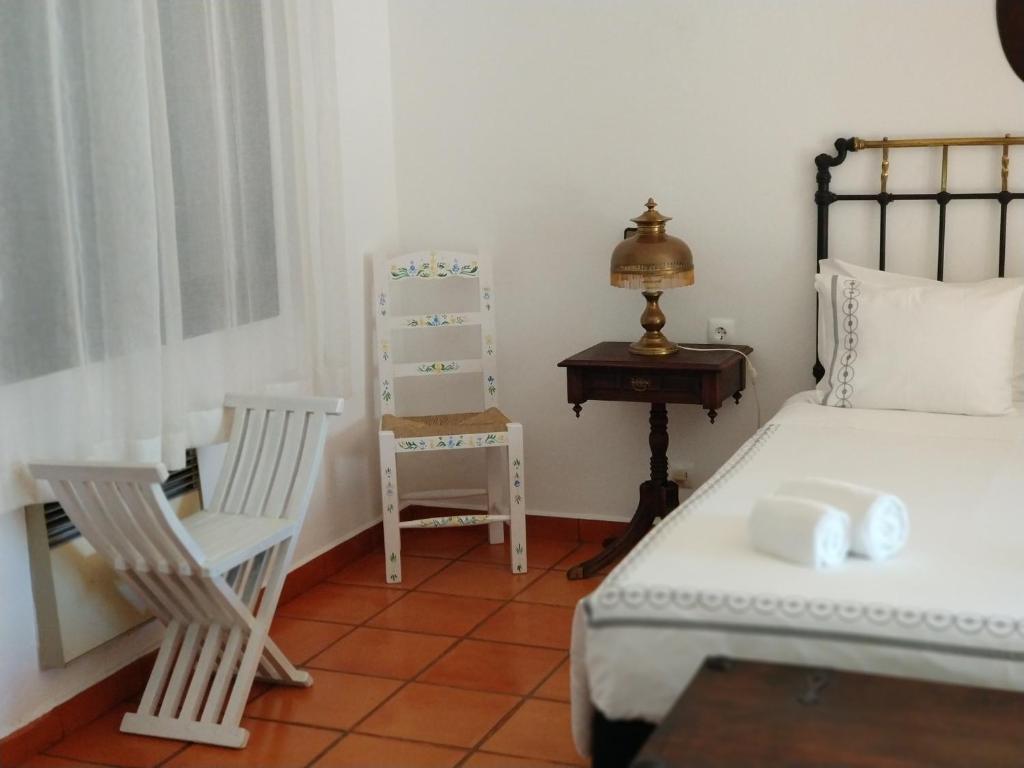 a bedroom with a bed and a chair and a table at Casa das Hortências By Alojamentos Vitinho - Vila Nova MIlfontes in Vila Nova de Milfontes