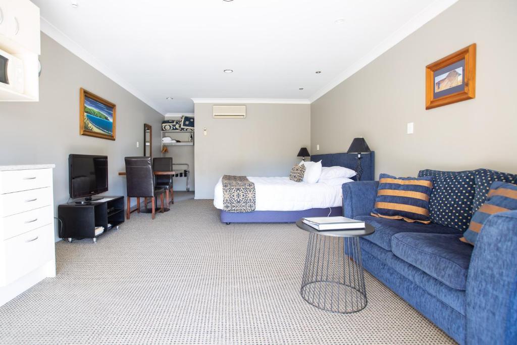 uma sala de estar com uma cama e um sofá azul em Murchison Motels em Murchison