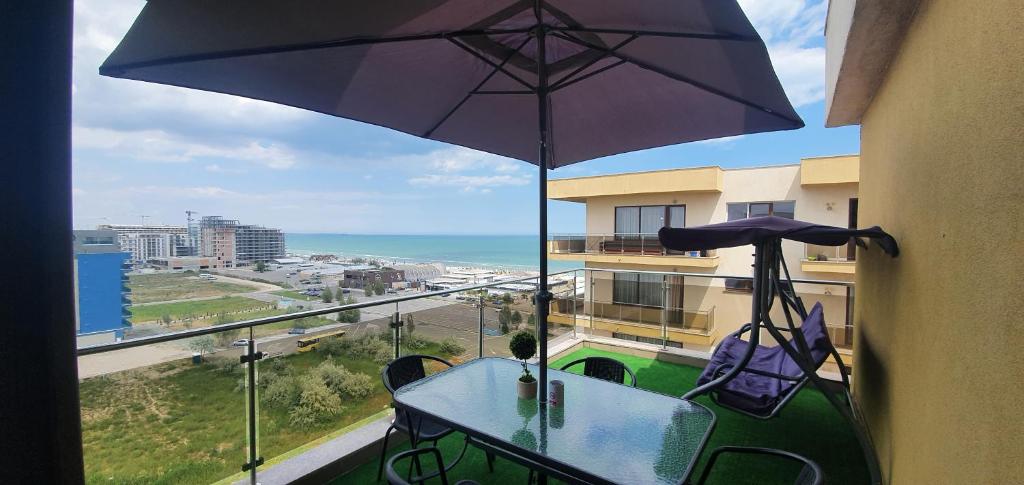 een tafel met een parasol op een balkon met uitzicht op de oceaan bij Ionut Summerland Apartments Mamaia in Mamaia