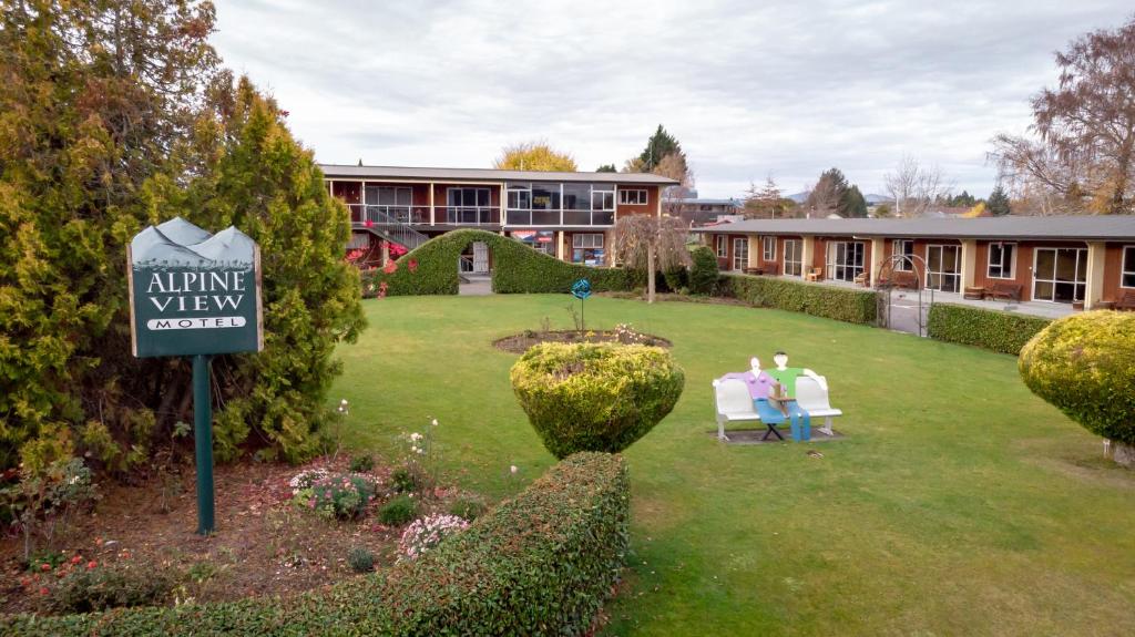 due persone sedute sulle sedie nel cortile di un edificio di Alpine View Motel a Te Anau