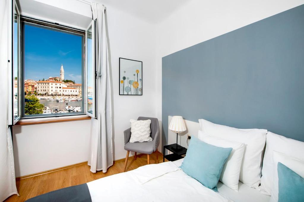 1 dormitorio con cama, ventana y silla en Apartment Mimi en Rovinj