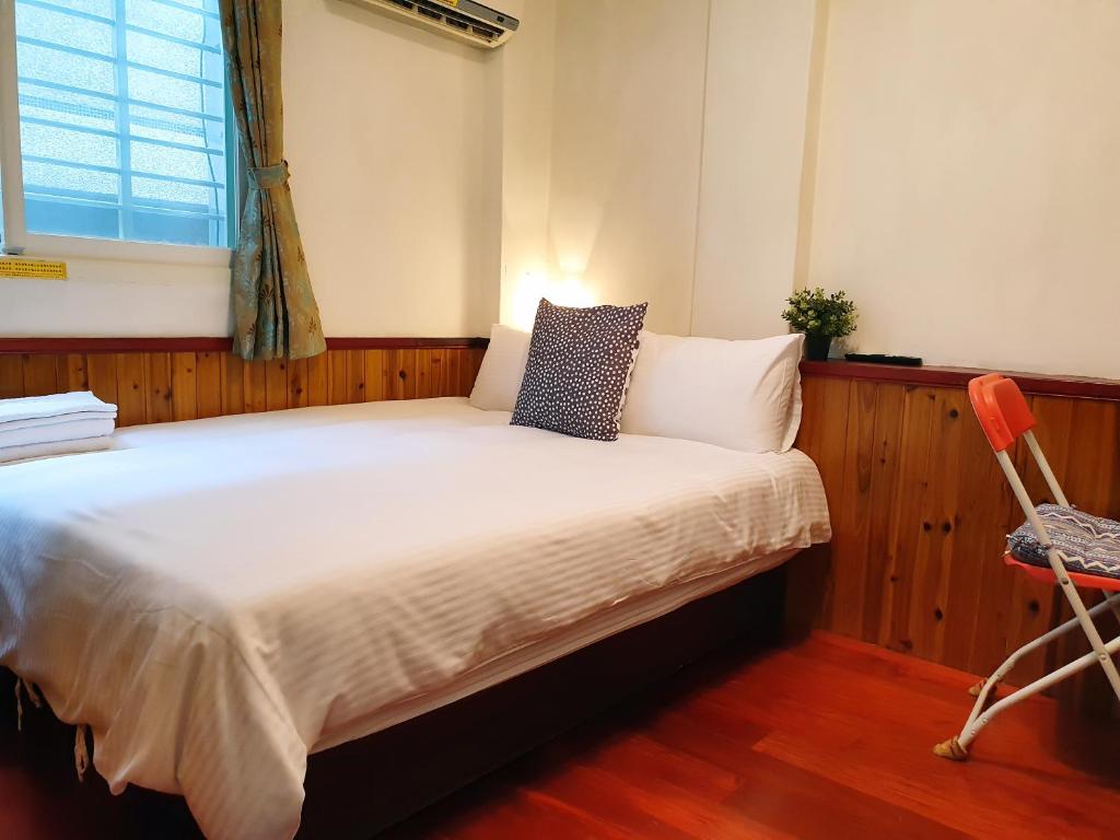 a bedroom with a bed with a window and a chair at Kao Mama B&amp;B in Jiufen