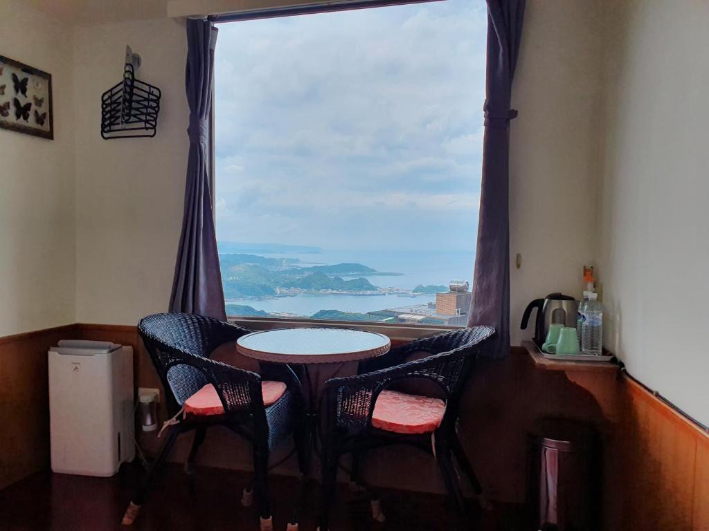 a table and chairs in a room with a large window at Kao Mama B&amp;B in Jiufen